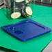 A blue Carlisle Smart Lid on a green food container with sliced cucumbers inside.