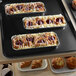 A black Cambro market tray on a table with pastries and muffins on it.