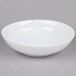 An Arcoroc white soup/cereal bowl on a gray surface.