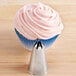 A cupcake with pink frosting on top with a design made using an Ateco closed star piping tip.