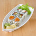 A Thunder Group Blue Bamboo melamine sushi boat filled with sushi on a wood table.