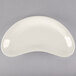 A Tuxton eggshell white crescent dish on a white surface.