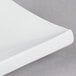 A close up of a Tokyia bone white rectangular porcelain platter with a curved edge.