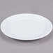 A white Cambro ceramic plate with a rim on a gray surface.