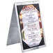 A Menu Solutions Alumitique aluminum table tent with picture corners holding a menu of desserts on a metal stand.