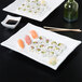 A CAC white rectangular porcelain platter with sushi on it.
