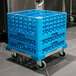 A blue Carlisle glass rack dolly with wheels and blue plastic crates on it.