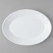 An Arcoroc white opal oval platter with a white rim on a gray surface.