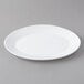 An Arcoroc white opal oval platter on a gray surface.