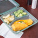 A jade green GET 3-compartment reusable Eco-Takeouts container with a burrito, chips, and a drink.
