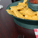A bowl of salsa and chips in a jalapeno-themed round deli server.