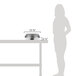 A woman standing next to a stainless steel food pan on a table.