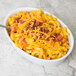 A white porcelain oval deep dish platter filled with macaroni and cheese topped with bacon and cheese.