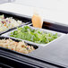 A white GET melamine food pan filled with salad on a salad bar counter.