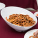 A white slanted melamine bowl filled with pretzels on a table.