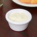 A white Carlisle fluted melamine ramekin filled with white sauce.