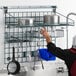 A man reaching up to hang a Metro SmartWall G3 task station shelf for dishes.