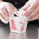 A person in gloves opening a Fold-Pak Pagoda Chinese take-out container on a counter.