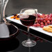 A Chef & Sommelier Cabernet wine glass filled with red wine next to a plate of grapes and crackers.
