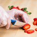A person using a blue Mercer Millennia paring knife to cut a strawberry.