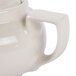 A close-up of a Hall China ivory teapot with a handle.