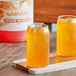 A couple of glasses of Narvon orange liquid on a table.