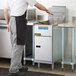 A man in a white shirt and apron using an Anets natural gas tube fired fryer in a commercial kitchen.