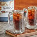Two glass mugs of Narvon Old Fashioned Root Beer with ice and brown liquid on a wooden table.