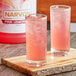 Two glasses of Narvon pink lemonade with ice on a wooden surface.