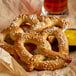 A close up of a SuperPretzel soft pretzel with mustard and a glass of beer.