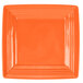 A close up of a Tuxton Concentrix papaya orange square plate with a white corner.
