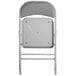 A back view of a Lancaster Table & Seating gray fabric folding chair with a padded seat.