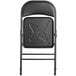 A black Lancaster Table & Seating folding chair with a metal star on the back.