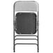 The back of a Lancaster Table & Seating grey fabric folding chair with a black frame.