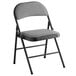 A dark grey fabric Lancaster Table & Seating folding chair with a padded seat.