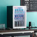 A Galaxy black countertop display refrigerator full of cans of soda.
