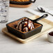 A Vollrath pre-seasoned cast iron square skillet with ice cream and chocolate sauce.