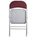 The back of a Lancaster Table & Seating burgundy fabric folding chair with a padded seat.