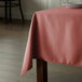 A table with a rectangular mauve tablecloth on it.