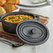 A Vollrath pre-seasoned cast iron oval cover on a mini Dutch oven filled with food.