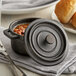 A Vollrath pre-seasoned mini cast iron pot with beans and bread on a table.