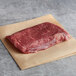 A Warrington Farm Meats frozen sirloin steak on brown paper.