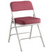 A Lancaster Table & Seating burgundy fabric folding chair with a white frame.