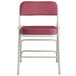 A Lancaster Table & Seating burgundy fabric folding chair with white frame and padded seat.
