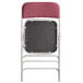 The back of a Lancaster Table & Seating burgundy fabric folding chair with a cushion.