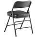 A Lancaster Table & Seating black folding chair with a padded seat.