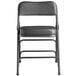 A black Lancaster Table & Seating folding chair with a black padded seat.