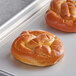 Two J & J Snack Foods Bavarian Bakery giant pretzel rolls on a baking sheet.