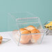 A clear Cal-Mil stackable food bin with rolls inside on a bakery display counter.