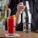 A person holding a Libbey Newton stackable beverage glass and pouring a red drink into it.